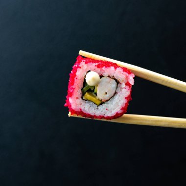 Japon suşisi kırmızı uçan balık yumurtası Tobiko havyarı koyu arka planda izole edildi. Kaliforniya usulü somon, salatalık, Norveç yosunu ve pilavına sarılmış avokado. Tabak izolasyonu