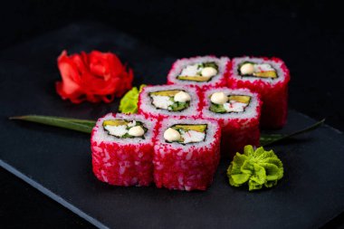 Japon suşisi kırmızı uçan balık yumurtası Tobiko havyarı koyu arka planda izole edildi. Kaliforniya usulü somon, salatalık, Norveç yosunu ve pilavına sarılmış avokado. Tabak izolasyonu