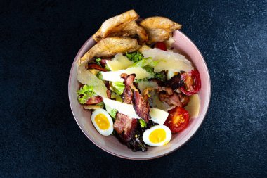 Sıcak salata, dana eti ve krem peynirli, tabakta ve koyu arkaplanda.