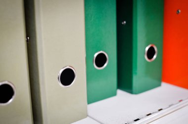 Close up on multicolored office folders on the bookshelf backgrounds. Many working stationery, stacked records. Different color spectrum documents. Educational or financial file-box object supplies