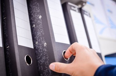 Kitaplığın arka planındaki ofis dosyalarını kapat. Bir sürü renkli kırtasiye malzemesi, istiflenmiş sipariş kayıtları. Farklı renk spektrumu. Eğitimsel ya da finansal nesneler