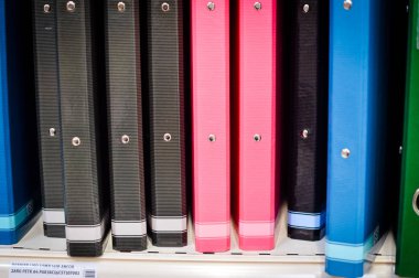Close up on multicolored office folders on the bookshelf backgrounds. Many working stationery, stacked records. Different color spectrum documents. Educational or financial file-box object supplies