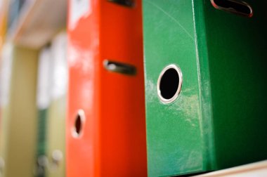 Close up on multicolored office folders on the bookshelf backgrounds. Many working stationery, stacked records. Different color spectrum documents. Educational or financial file-box object supplies