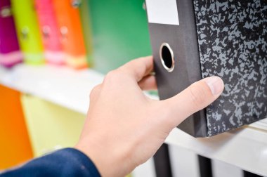 Kitaplığın arka planındaki ofis dosyalarını kapat. Bir sürü renkli kırtasiye malzemesi, istiflenmiş sipariş kayıtları. Farklı renk spektrumu. Eğitimsel ya da finansal nesneler