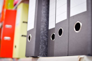 Close up on multicolored office folders on the bookshelf backgrounds. Many working stationery, stacked records. Different color spectrum documents. Educational or financial file-box object supplies