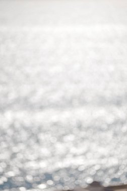 Parlak suyun üzerindeki bulanık güneş ışığı yansımaları soyutlaşmıştı. Sıvı canlı doku deseni, parlak güneşli arkaplan