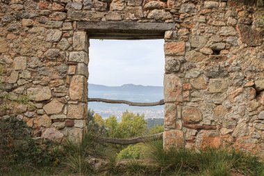 Katalonya, İspanya 'daki dağlara ve vadiye bakan kırsal ahşap pencere çerçeveli antik taş duvar. Tarih, miras ve perspektif kavramı.
