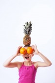 Vidám gyermek játszó, narancs, ananász, banán. Az egészséges táplálkozás és a vegetarianizmus.