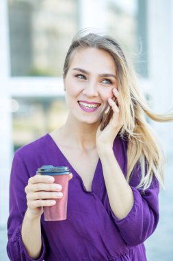 Gülümseyen kız telefonda konuşurken ve kahve içme. Yaşam tarzı, kentsel, iş kavramı