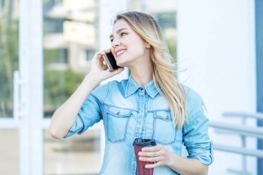 Neşeli kadın telefonla konuşuyor ve kahve içiyor. Yaşam tarzı, kentsel, iş kavramı