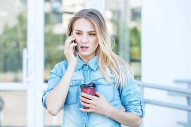 Genç kadın telefonla konuşuyor ve kahve içiyor. Yaşam tarzı, kentsel, iş kavramı