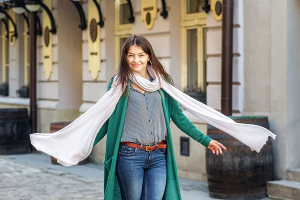 Una joven camina por la ciudad con una larga bufanda. El concepto de moda, estilo de vida, ciudad — Foto de Stock