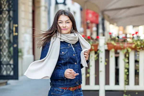 Seorang wanita muda berjalan di jalan dengan syal. Konsep gaya hidup, fashion, perkotaan — Stok Foto