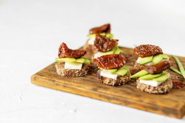 Gemide peynirli sandviçler, avokado ve kurutulmuş domates. Gıda, sağlıklı gıda ve vejetaryenler için konsept.