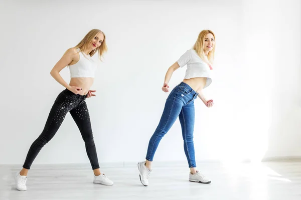Two girls dancing in jeans and sneakers. The concept of sport, dance and lifestyle — Stock Photo, Image