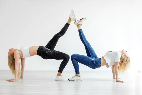 Dua gadis ramping menari dengan celana jeans dan sepatu kets. Konsep olahraga, tari dan gaya hidup — Stok Foto