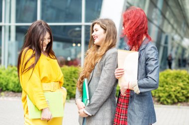 Üç öğrenci üniversitede konuşup gülüyor. Eğitim kavramı, dostluk ve insan grubu