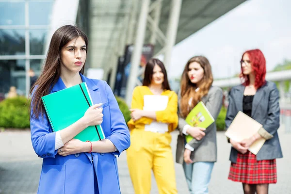 Una joven con un traje azul. Estudiante con una carpeta. Concepto educativo, exámenes, amistad y grupo de personas — Foto de Stock