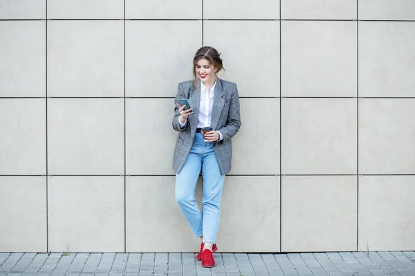 Mujer adulta está cerca de la pared con café. Comunicarse en Internet. Concepto de estilo de vida, urbano, empresarial, estudio — Foto de Stock