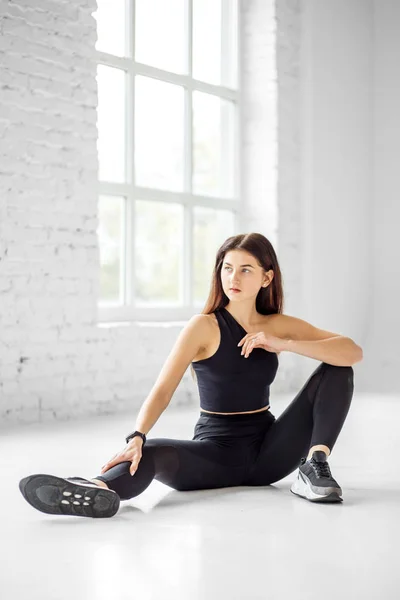 Una joven está sentada en el suelo en la clase de baile. El concepto de deportes, estilo de vida saludable, fitness, estiramiento . —  Fotos de Stock