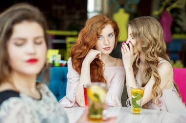 Young girls gossip behind the back of a friend. The concept of lifestyle, gossip, lies, friendship clipart