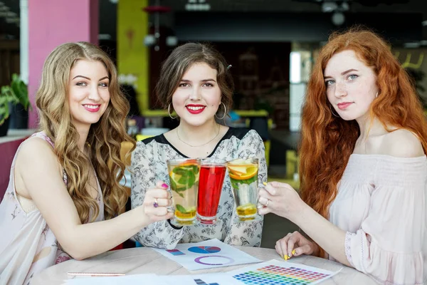 Üç kız nane, çilek ve narenciye lezzetli çay içmek. İçecek, toplantı, eğlence ve parti kavramı