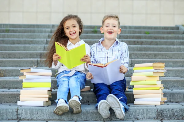 Twee schoolkinderen lezen boeken en lachen. Het concept is terug naar school, onderwijs, lezen, vriendschap en familie. — Stockfoto