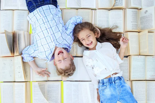 Los niños mienten en muchos libros. Los niños se ríen. Vista superior. El concepto es volver a la escuela, la educación, la lectura, la amistad —  Fotos de Stock