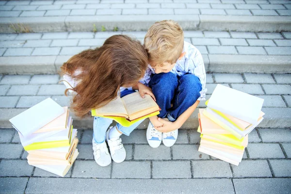 Kleine jongen en meisje studeren een boek. Het concept is terug naar school, onderwijs, lezen, vriendschap en familie — Stockfoto
