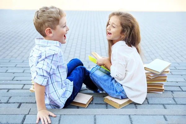 El niño y la niña felices están leyendo libros. El concepto es volver a la escuela, la educación, la lectura, la amistad y la familia —  Fotos de Stock