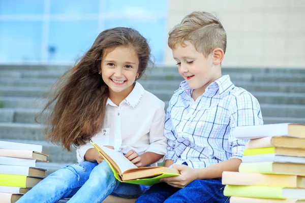 Gelukkige kleine jongen en meisje lezen een boek. Het concept is terug naar school, onderwijs, lezen, vriendschap en familie — Stockfoto