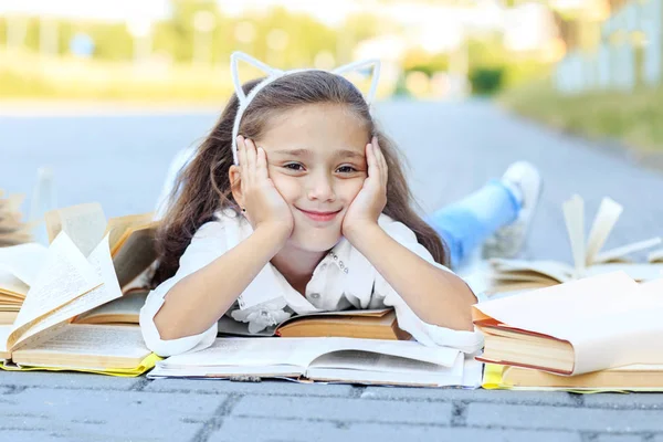 Weinig glimlachend meisje studeert studieboeken. Het concept is terug naar school, onderwijs, lezen, hobby's — Stockfoto