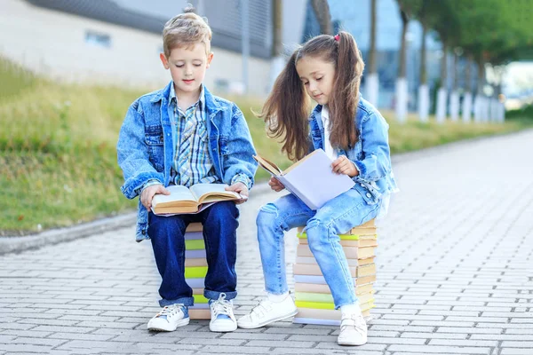 Los pequeños estudiantes leen libros de texto. El concepto es volver a la escuela, la educación, la lectura, la amistad y la familia . —  Fotos de Stock