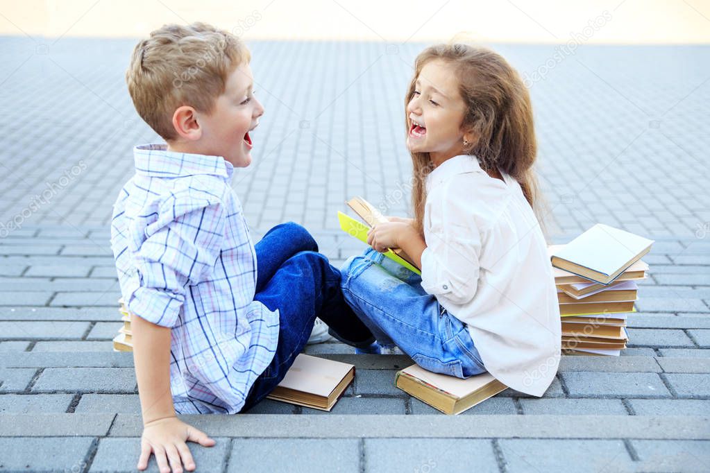 Happy boy and girl are reading books. The concept is back to school, education, reading, friendship and family