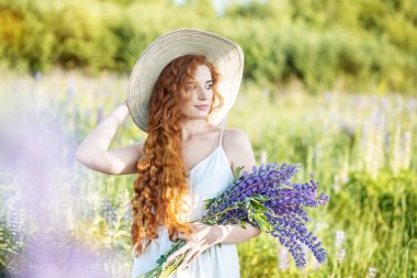 Lupins çiçek bir buket ile güzel bir kız. Uzun saçlı kadın. Konsept yaz, yaşam tarzı, seyahat ve güzellik
