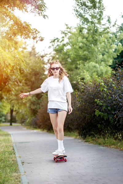 Jeune adolescente chevauchant une planche à roulettes dans le parc. Le concept de style de vie, de loisirs . — Photo