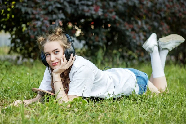 Красивая девушка-подросток слушает песни с наушниками в парке. Концепция образа жизни, отдыха . — стоковое фото