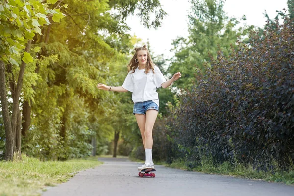 Fille gaie monte une planche à roulettes dans le parc. Le concept de style de vie, de loisirs . — Photo