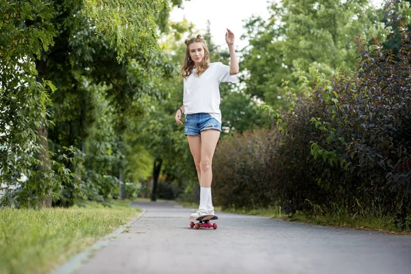 Uma jovem está montando um skate no parque. O conceito de estilo de vida, lazer . — Fotografia de Stock