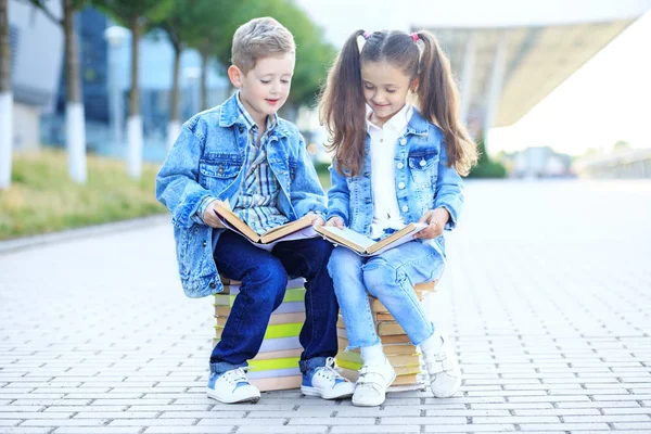 As crianças pequenas lêem muitos livros didáticos. O conceito está de volta à escola, educação, leitura, amizade e família . — Fotografia de Stock