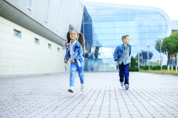 남동생과 여동생이 거리를 달리고 있습니다. 어린 시절, 가족, 교육의 개념. — 스톡 사진