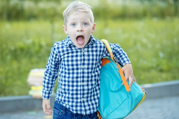 Surpris enfant se tient avec un sac à dos. Le concept d'apprentissage, d'école, d'esprit, de mode de vie et de réussite . — Photo