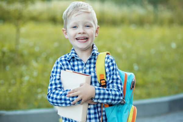 Happy little schoolboy with a backpack and books. The concept of