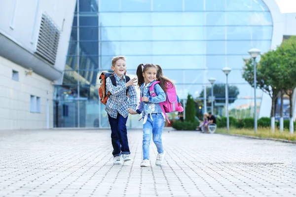 Los niños corren con mochilas de la escuela. El concepto es volver a la escuela, el estudio, la amistad . — Foto de Stock