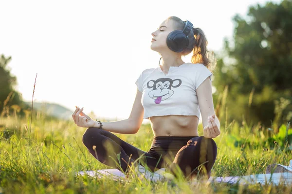 La chica escucha música en los auriculares. Una mujer está meditando. Concepto de estilo de vida, música, relajación . —  Fotos de Stock