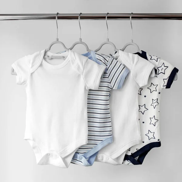A set of beautiful clothes for a newborn on hangers. Copy space. The concept of clothes, motherhood, fashion and newborn.