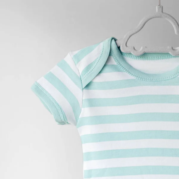 Striped clean clothes for a newborn on a hanger. Place for text. The concept of clothes, motherhood, fashion.