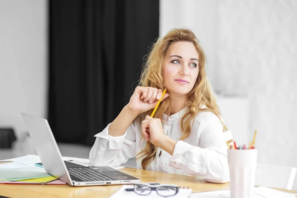 Hermosa mujer se sienta en una computadora y piensa. Concepto para negocios, trabajo, carrera . —  Fotos de Stock