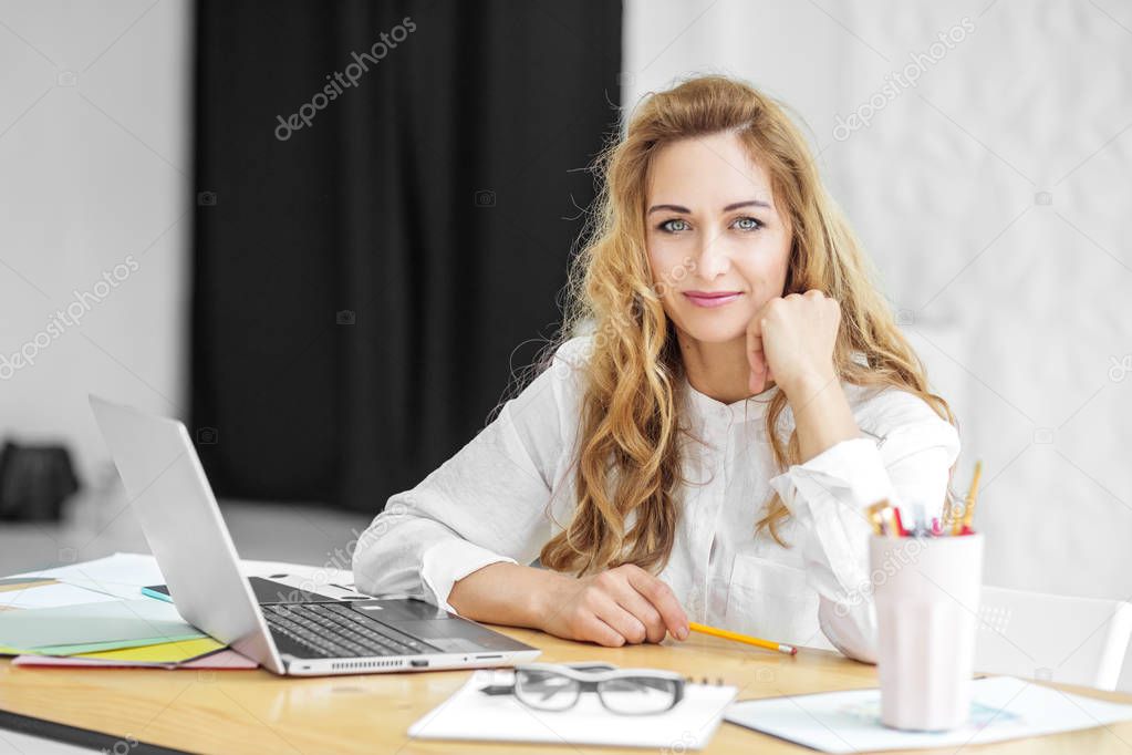 Beautiful woman sits at a desk. Concept for business, work, career.