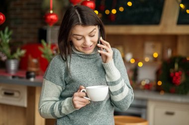 Güzel bir kadın cep telefonuyla konuşur. Kız çay içiyor. Kış konsepti, yaşam tarzı, mutlu noeller ve yeni yıl. Kış kavramı, yaşam tarzı, Noel ve Yeni Yıl.